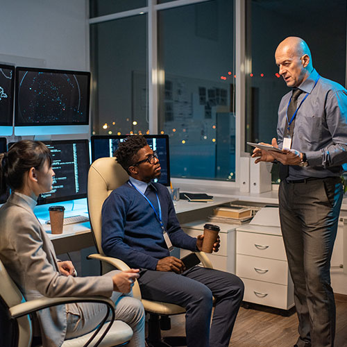 Confident mature manager with tablet interacting with two young subordinates