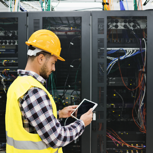 Young technician man working with tablet inside big data center room